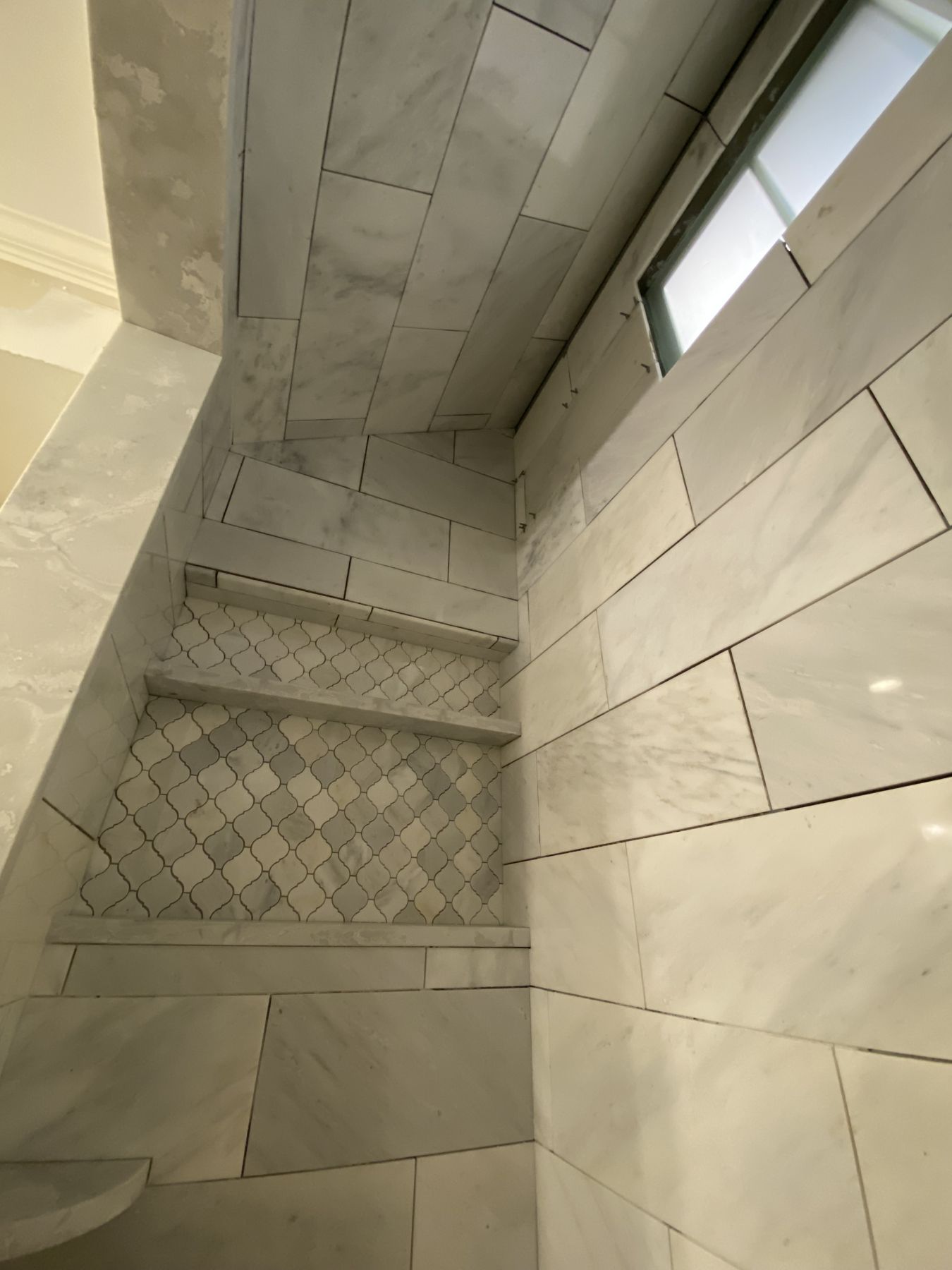 Marble shower niche with a mosaic tile base