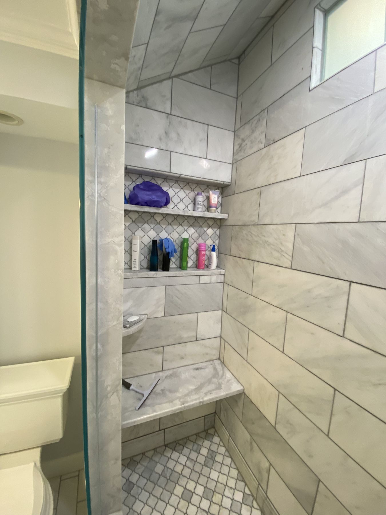 Marble tile shower with a built-in niche and bench