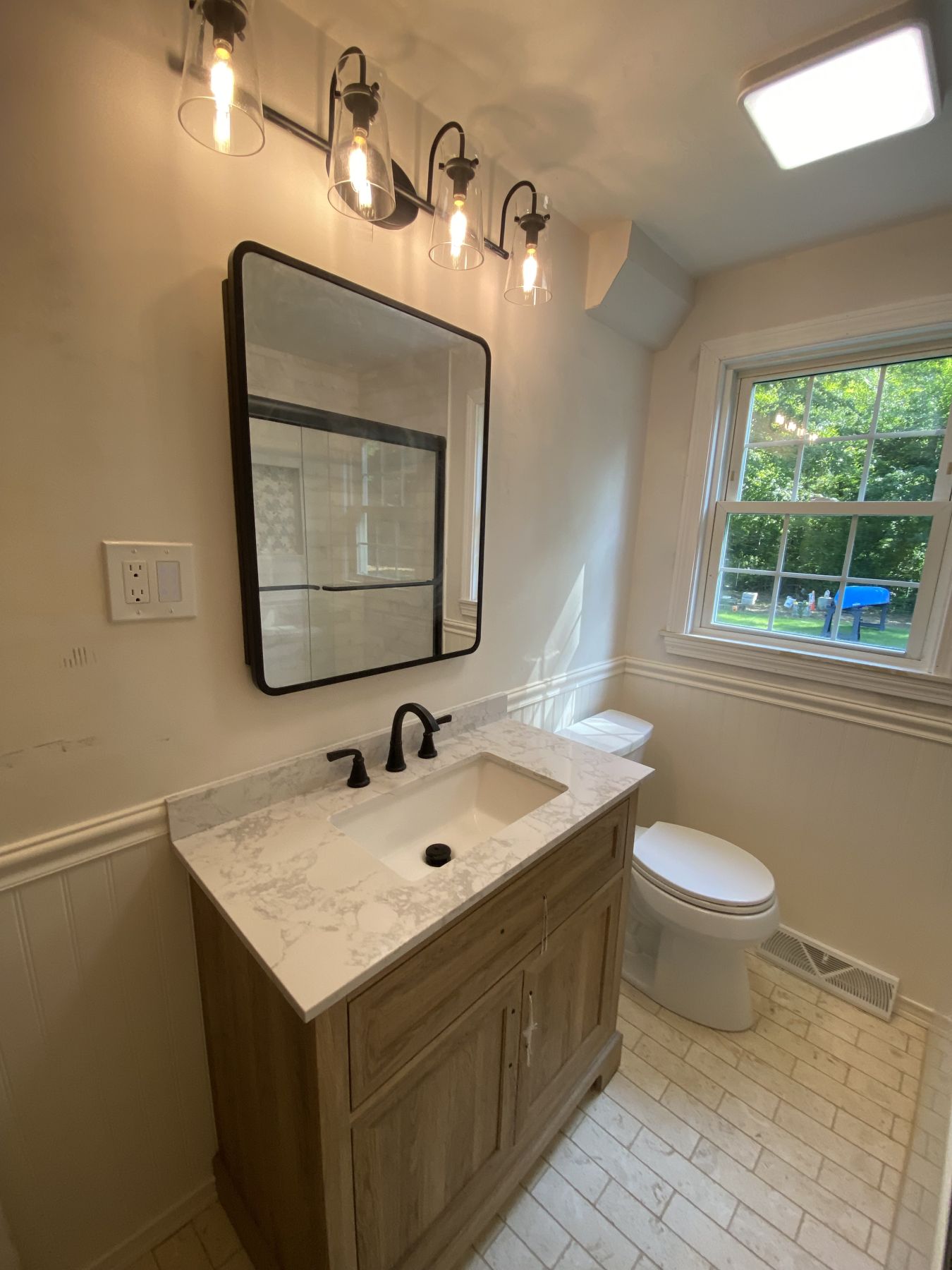 Bathroom vanity in wood with a stone top and framed mirror