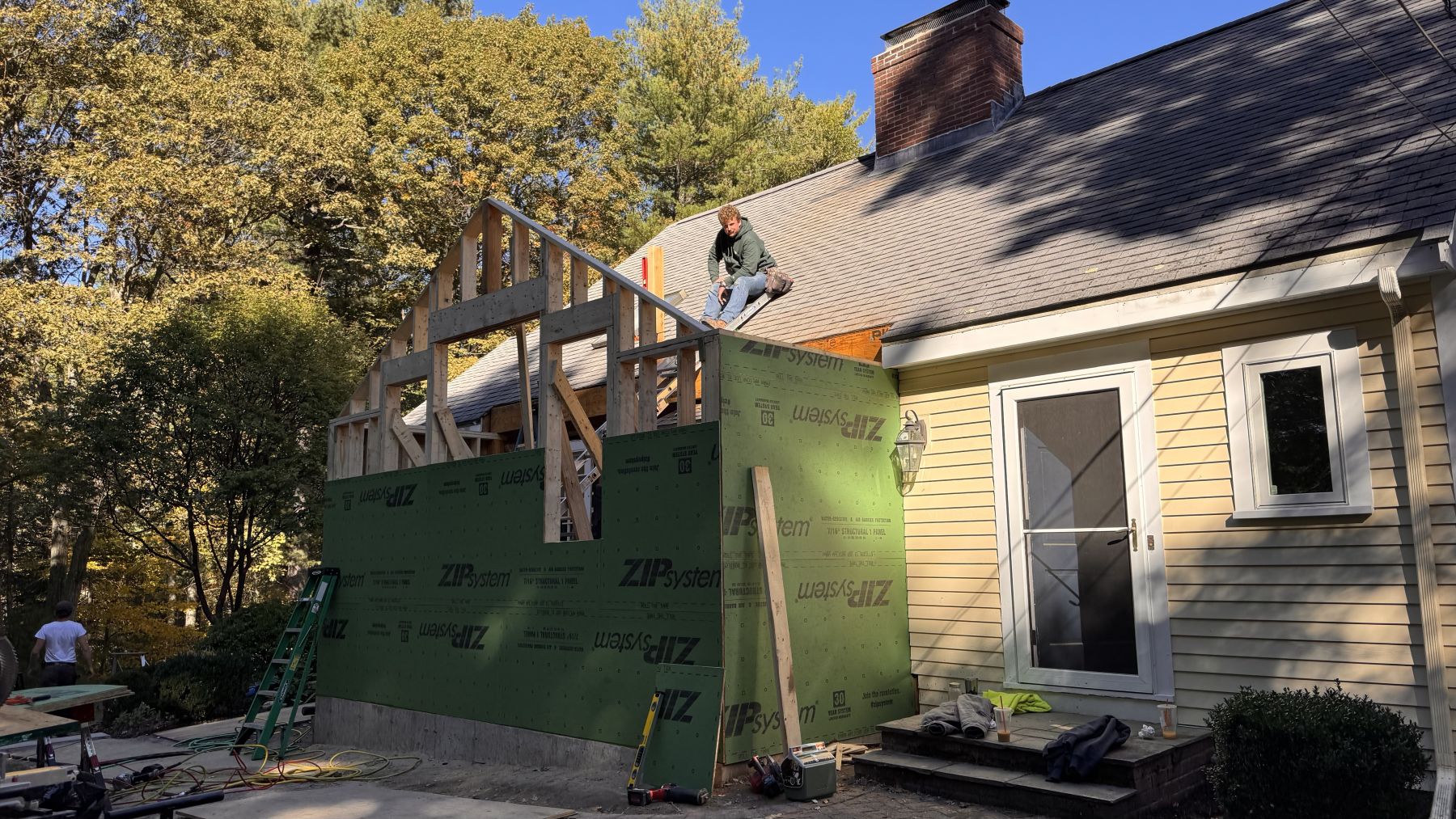 Jeffrey Wheeler on the roof of a framed addition, ZIP sheathing up and the crew working