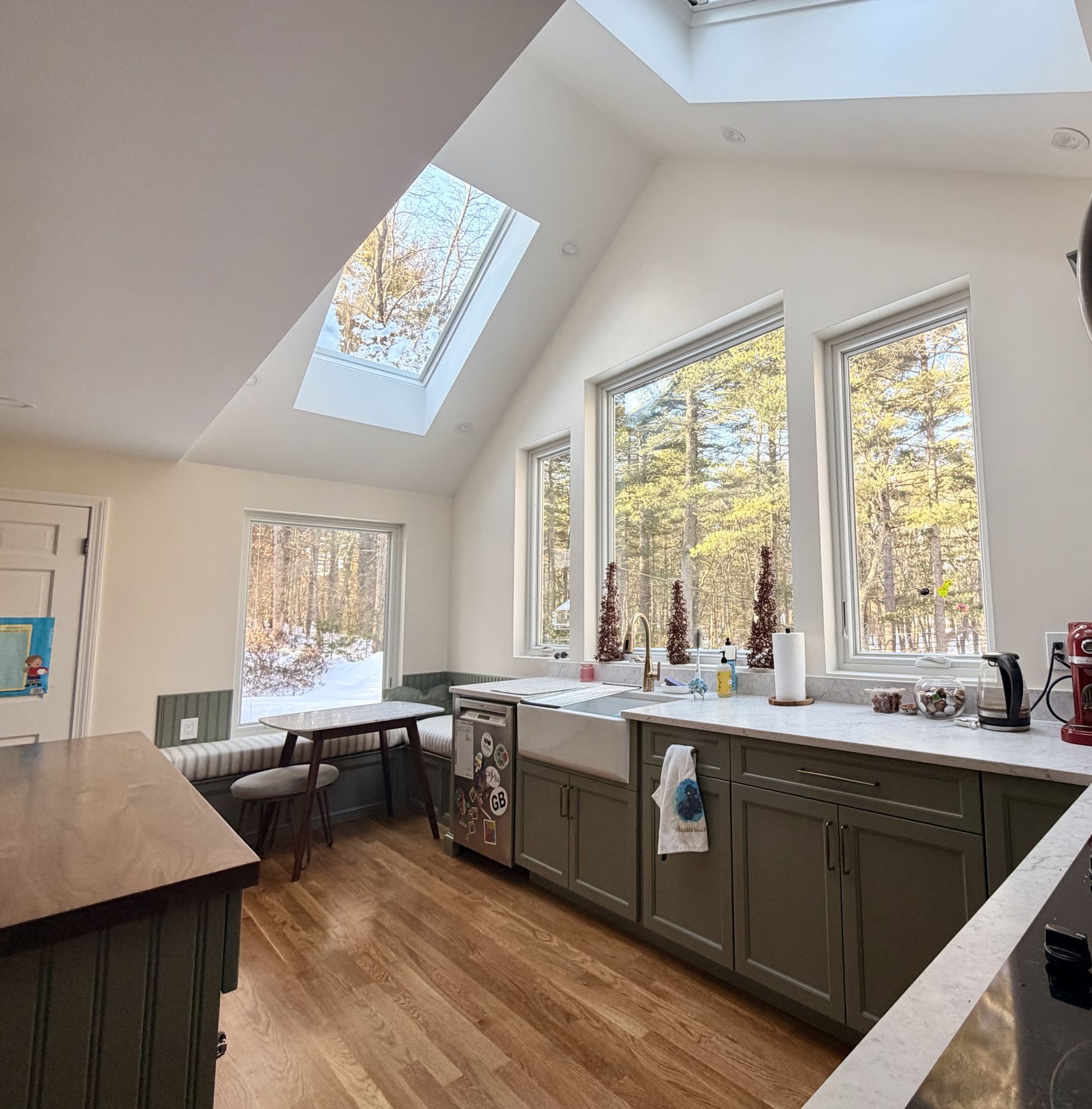 Kitchen under a cathedral ceiling with skylights and a full window wall