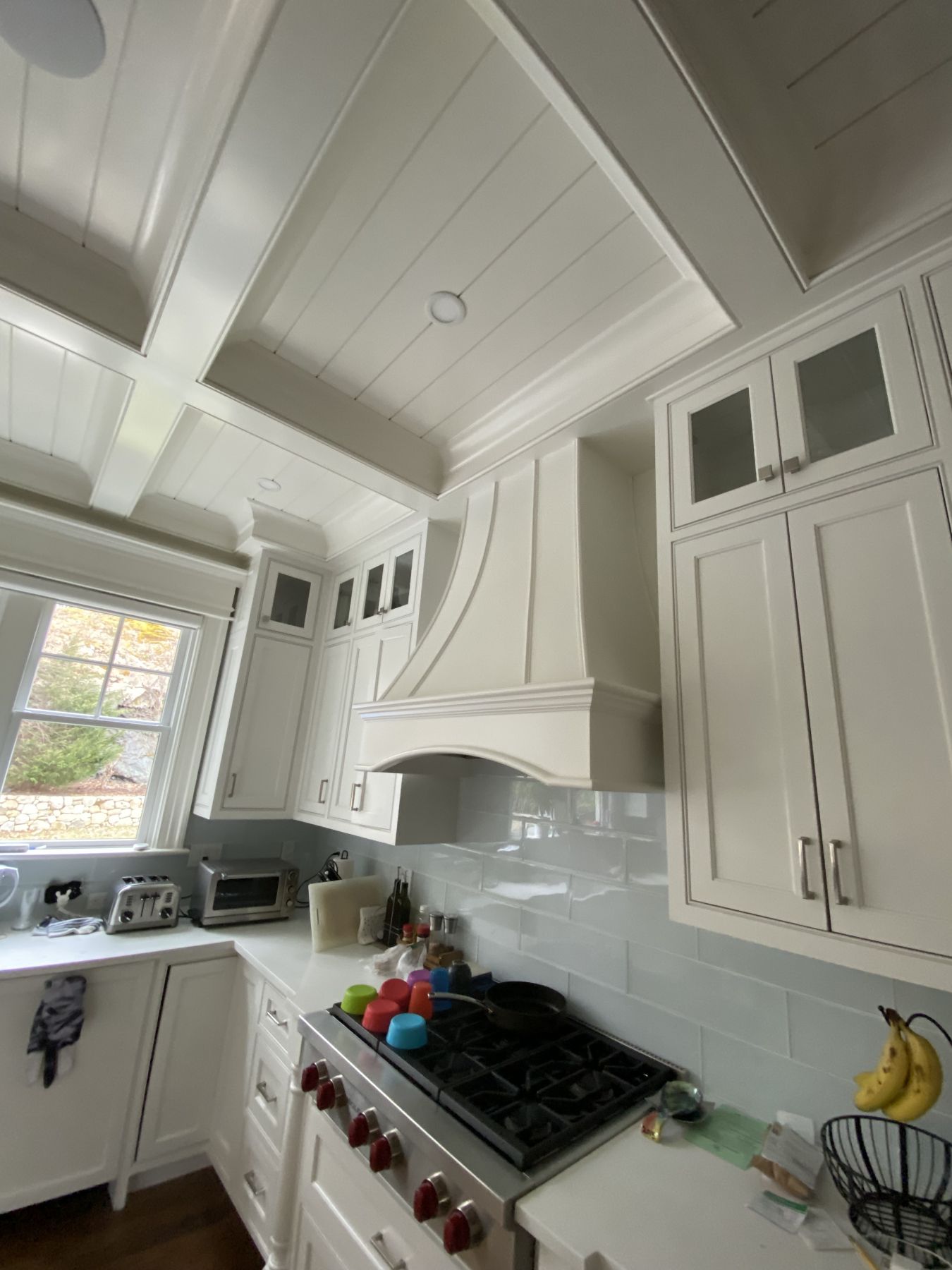 White kitchen cabinetry with a custom range hood and tile backsplash