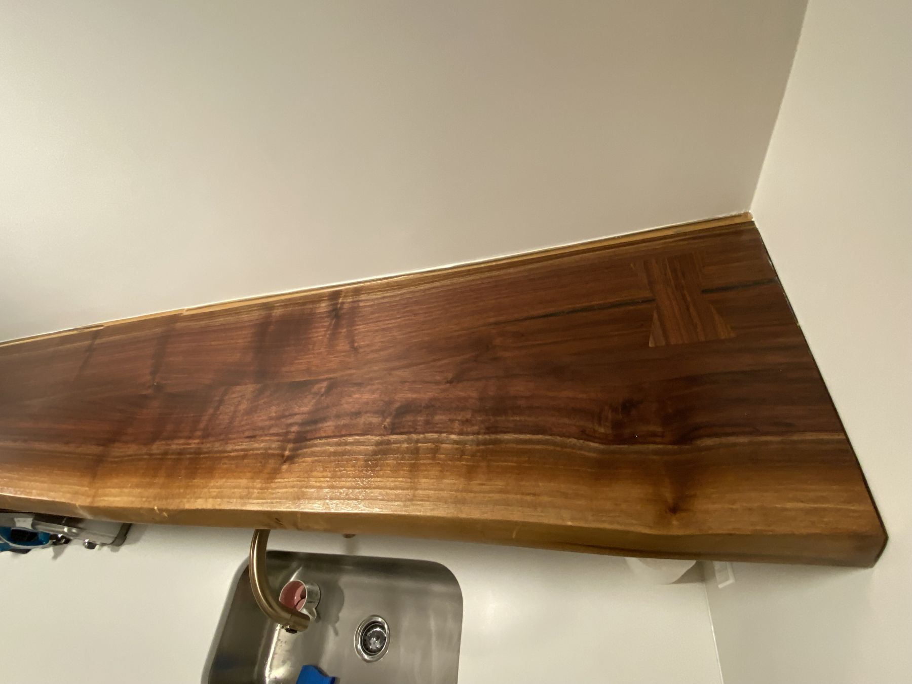 Live-edge walnut shelf mounted over a bar